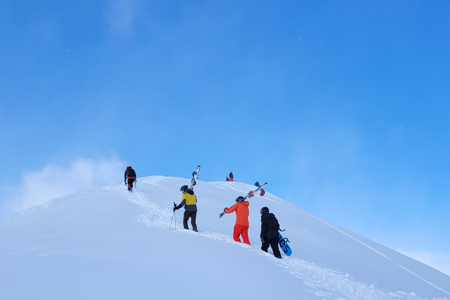 Group of skiers on a snowy mountain with a clear blue sky